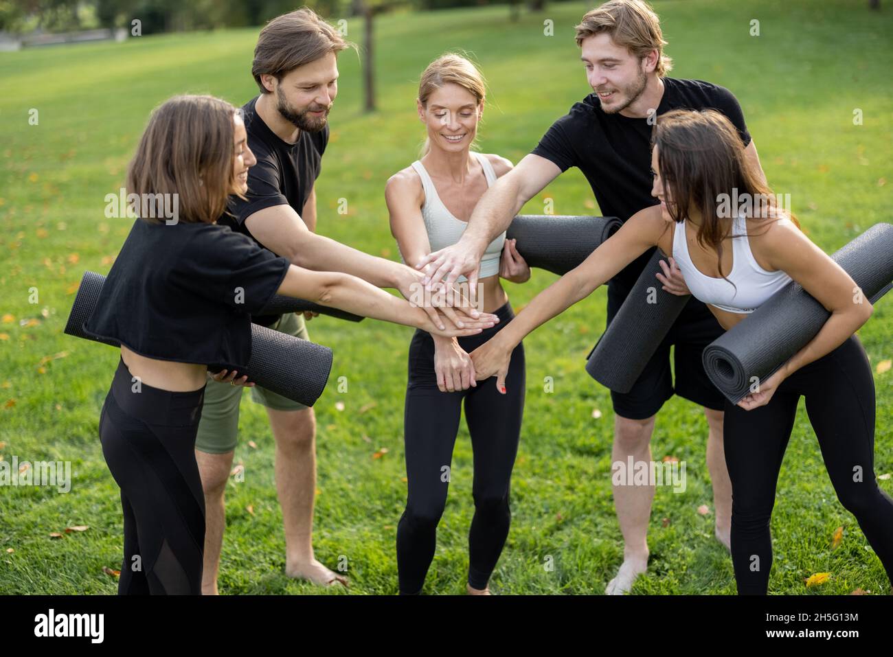 Le persone con materassini per il fitness si trovano in un prato verde Foto Stock