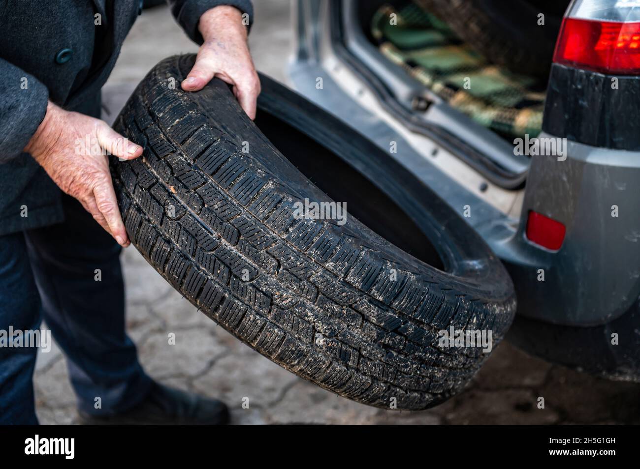 l'uomo scarica una serie di pneumatici di cambio dal bagagliaio, concetto di cambio pneumatici stagionale, closeup Foto Stock