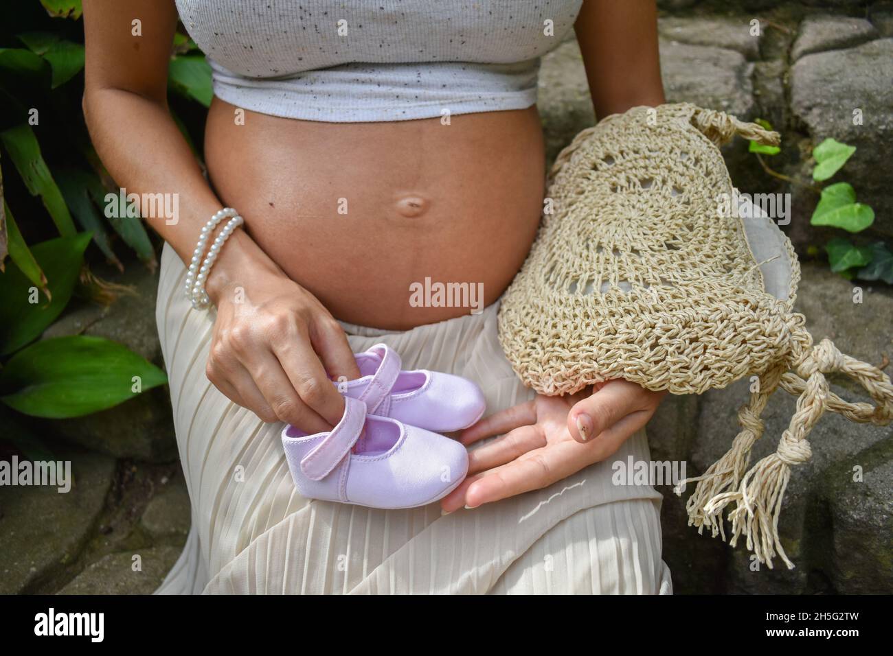 Primo piano della pancia di una donna incinta caucasica seduta all'aperto Foto Stock