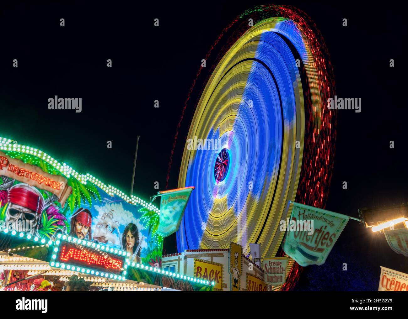 Molln, Germania, 06 novembre 2021: Lunga esposizione in una fiera annuale di divertimento viaggiante con giri veloci e bancarelle illuminate, colorato divertimento astratto b Foto Stock