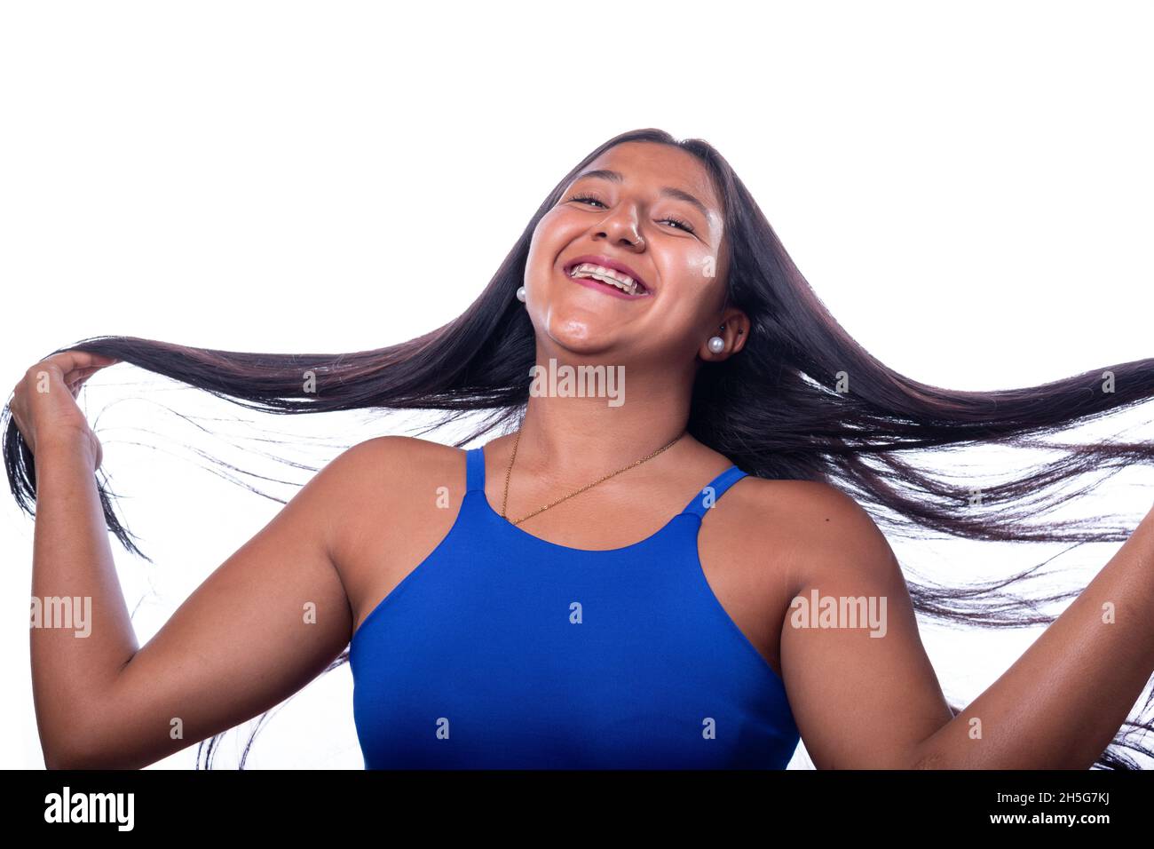 Donna muovendo i capelli con le mani sorridendo. Donna nera di etnia latina isolata su tutto sfondo bianco. Foto Stock
