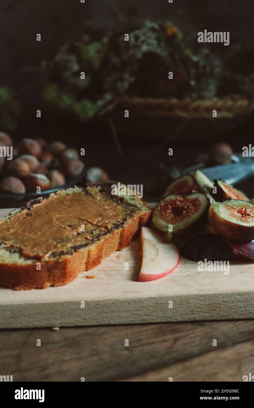 Vassoio di legno con torta al cioccolato e fichi succosi e mele affettati con fondo nocciola Foto Stock