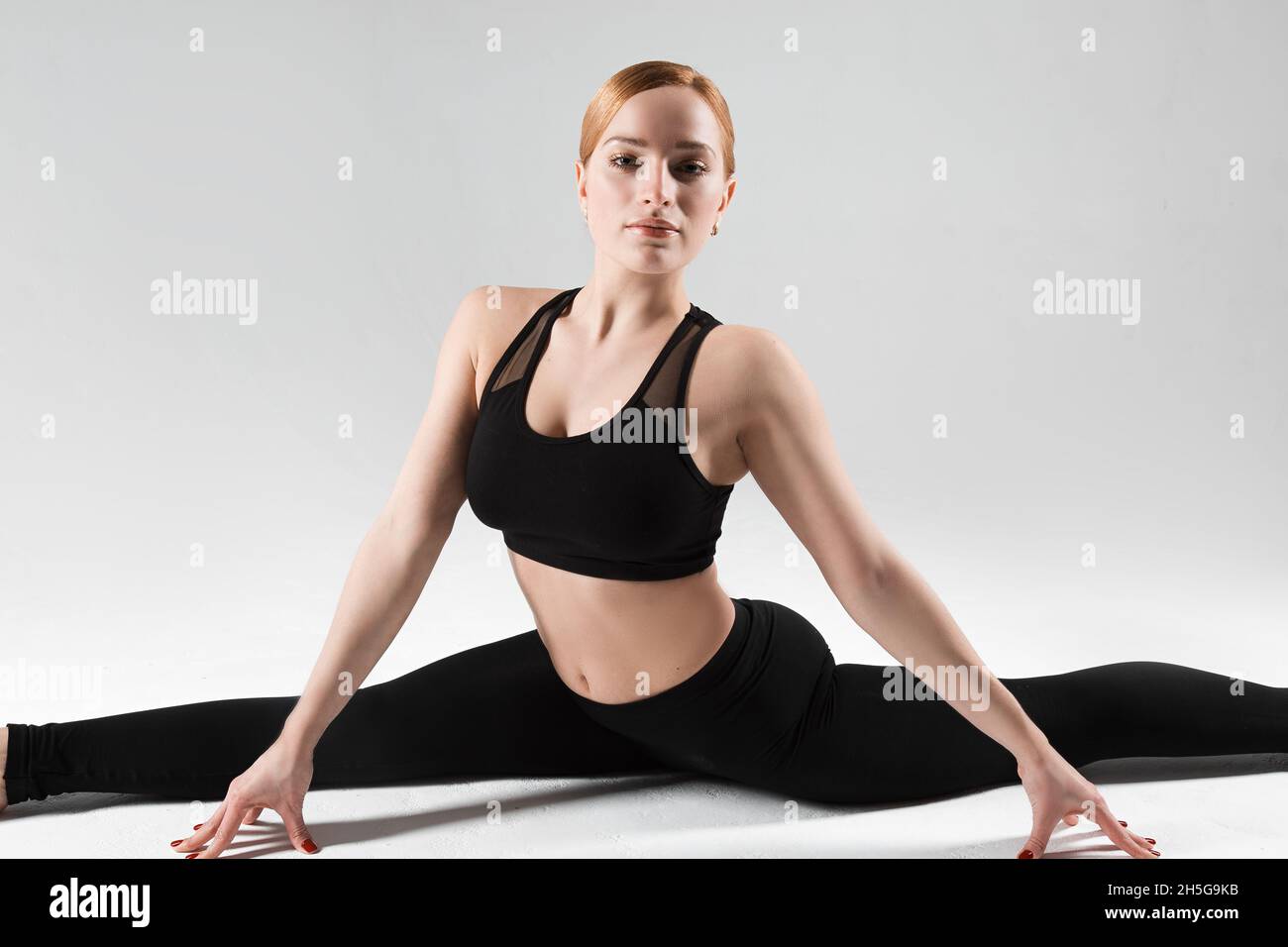 Un addestratore professionale di yoga e pilates mostra le esercitazioni da yoga, pilates, stretching ed altri tipi di idoneità su un tappeto con l'apparecchiatura, con i fitnes Foto Stock