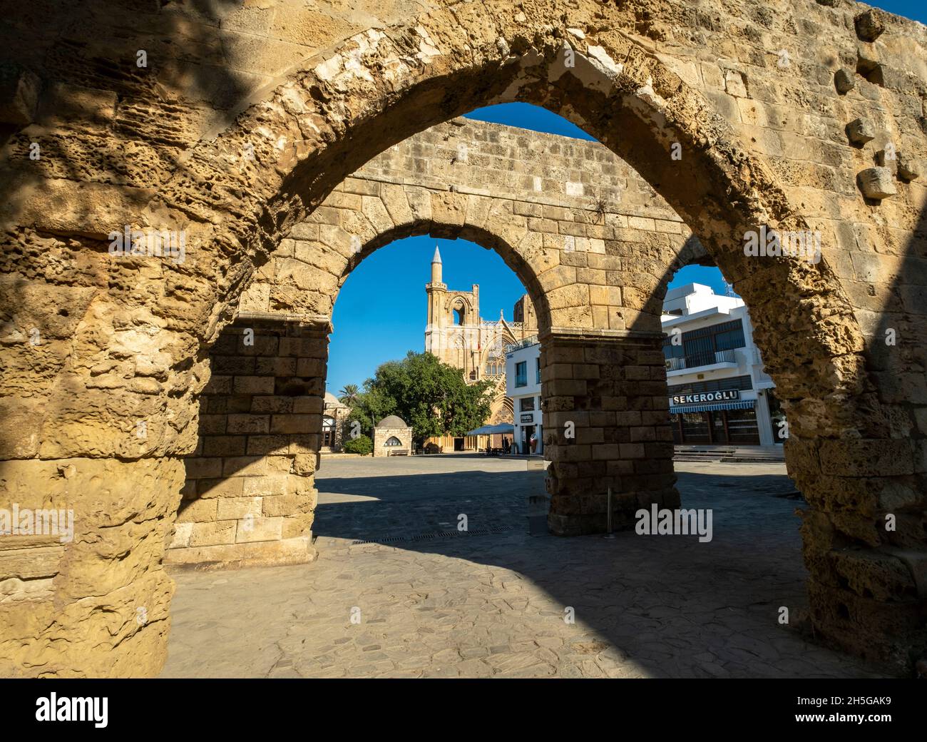 Moschea di Lala Mustafa Pasha, incorniciata attraverso gli archi del Palazzo Veneziano, Piazza Namik Kemal, Famagosta, Cipro del Nord. Foto Stock