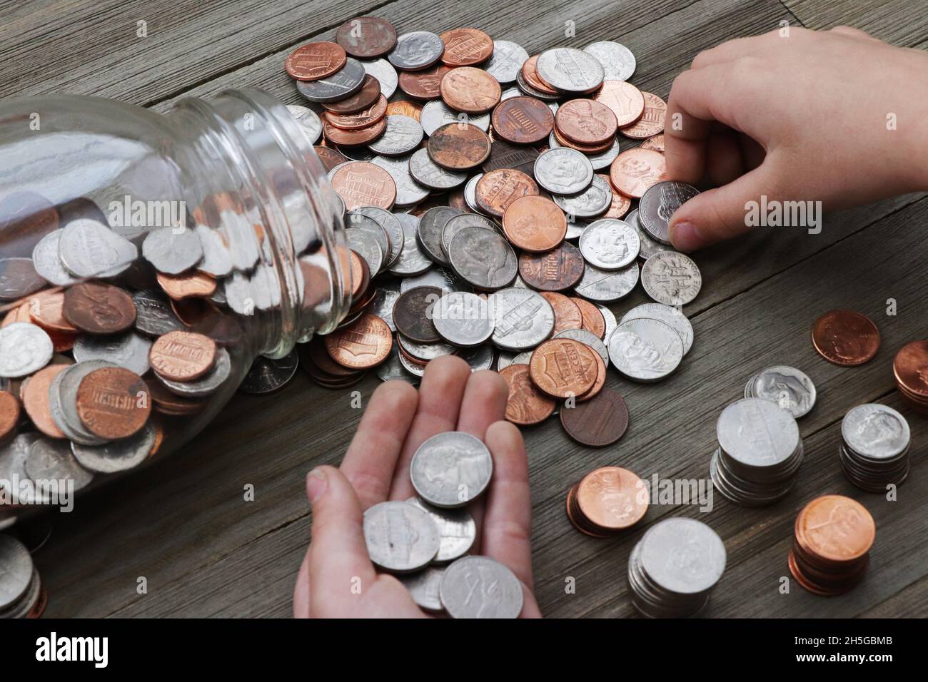 I bambini contano le monete da un vaso di vetro Foto Stock