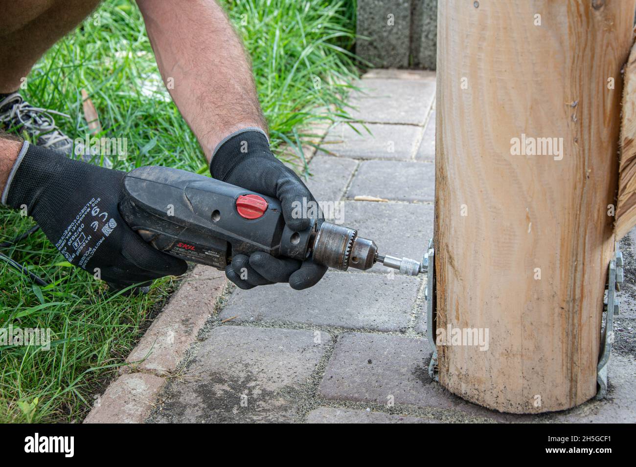 Gli operatori che indossano i guanti devono utilizzare un cacciavite elettrico per serrare la vite. Foto Stock