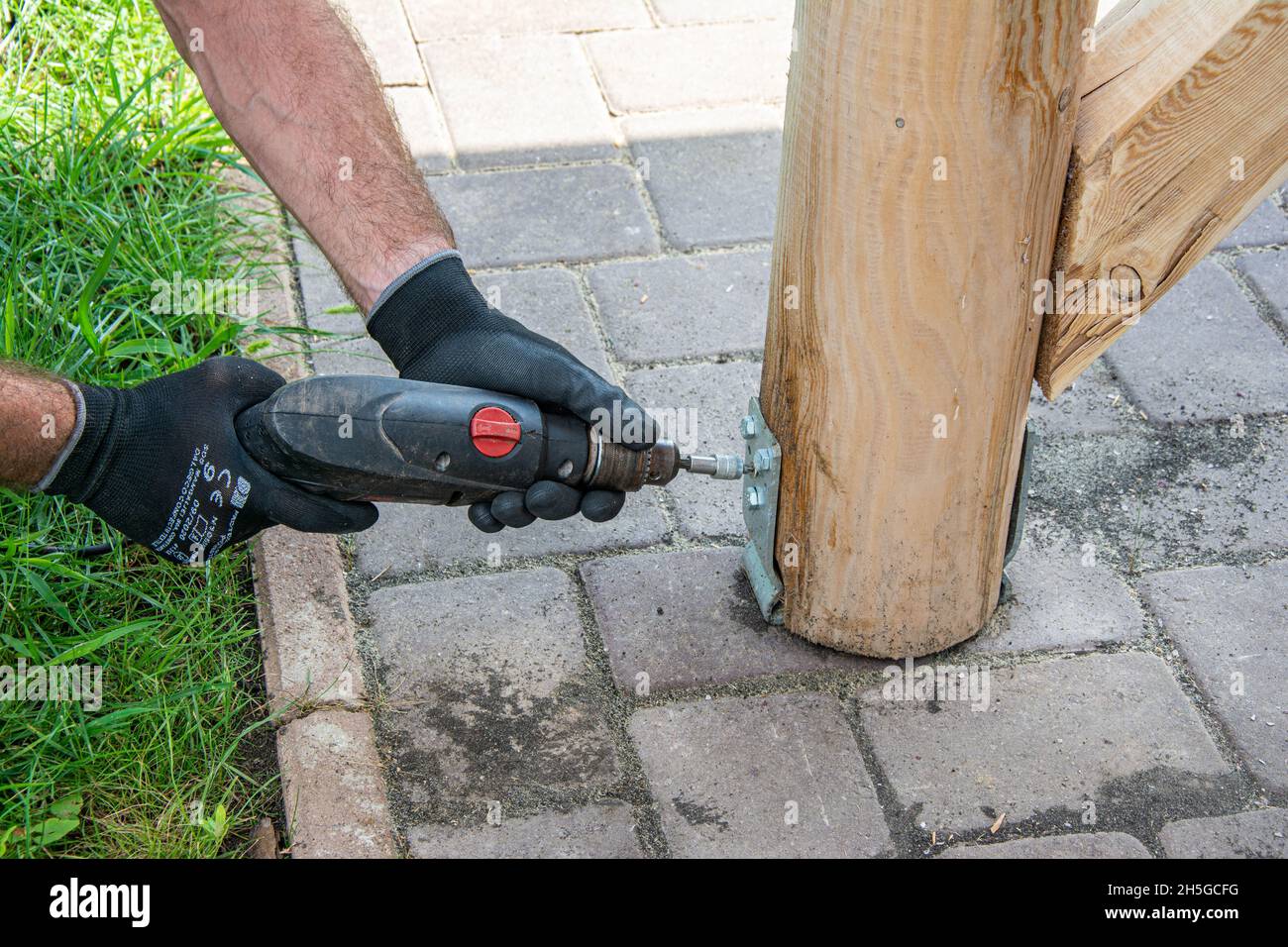 Gli operatori che indossano i guanti devono utilizzare un cacciavite elettrico per serrare la vite. Foto Stock
