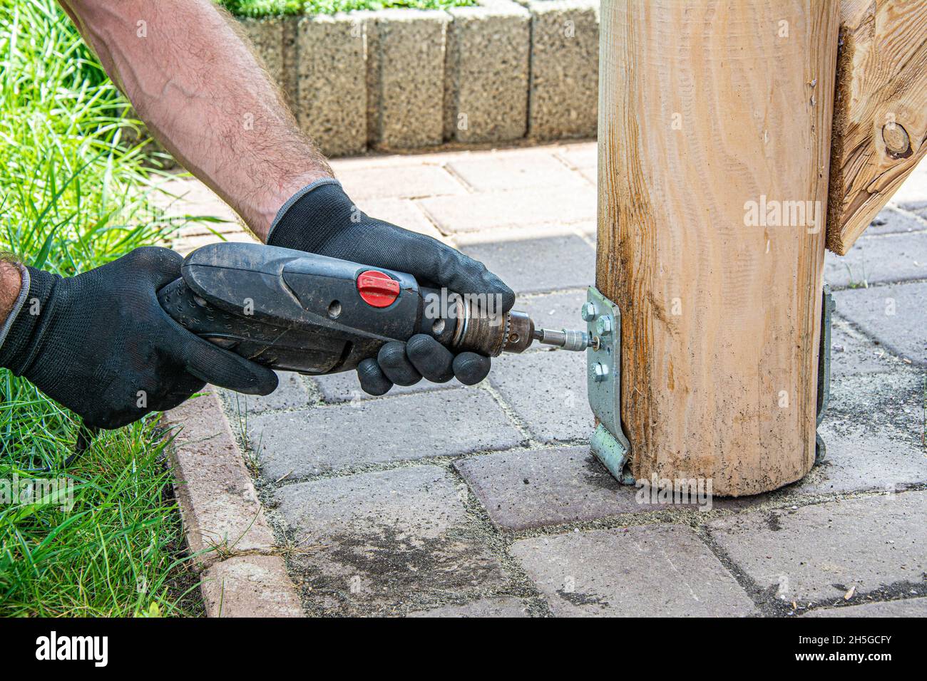 Gli operatori che indossano i guanti devono utilizzare un cacciavite elettrico per serrare la vite. Foto Stock