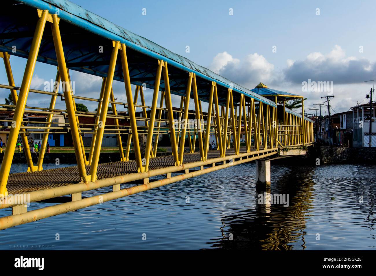 Nazaré, Bahia, Brasile - 11 gennaio 2016: Passerella pedonale in ferro su un fiume di colore giallo e blu. Riflessione in acqua. Foto Stock