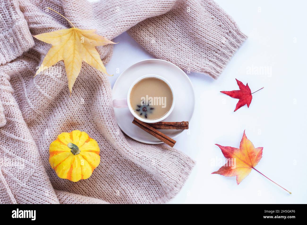Caffè caldo con anice stellato e cannella in una tazza, zucca gialla e foglie d'autunno. Vista dall'alto, piatto. Concetto di caduta Foto Stock