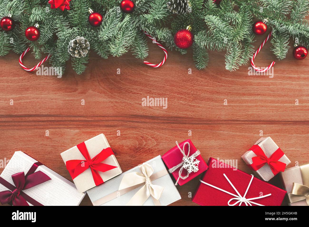Sfondo natalizio con rami di abete, decorazioni di Capodanno e scatole regalo su sfondo di legno. Vista dall'alto, disposizione piatta, spazio di copia Foto Stock
