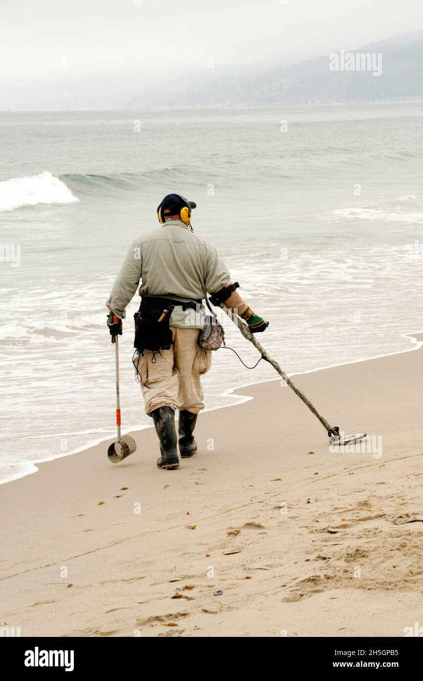 Uomo con un metal detector a caccia di tesori in spiaggia Foto stock - Alamy