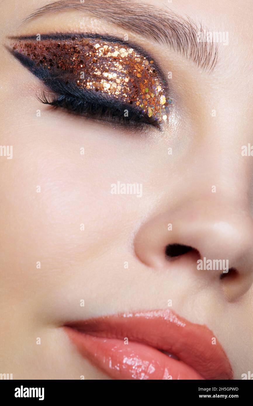 Primo piano di faccia femminile con Vogue dorate lucenti occhi trucco. Occhi chiusi. Foto Stock
