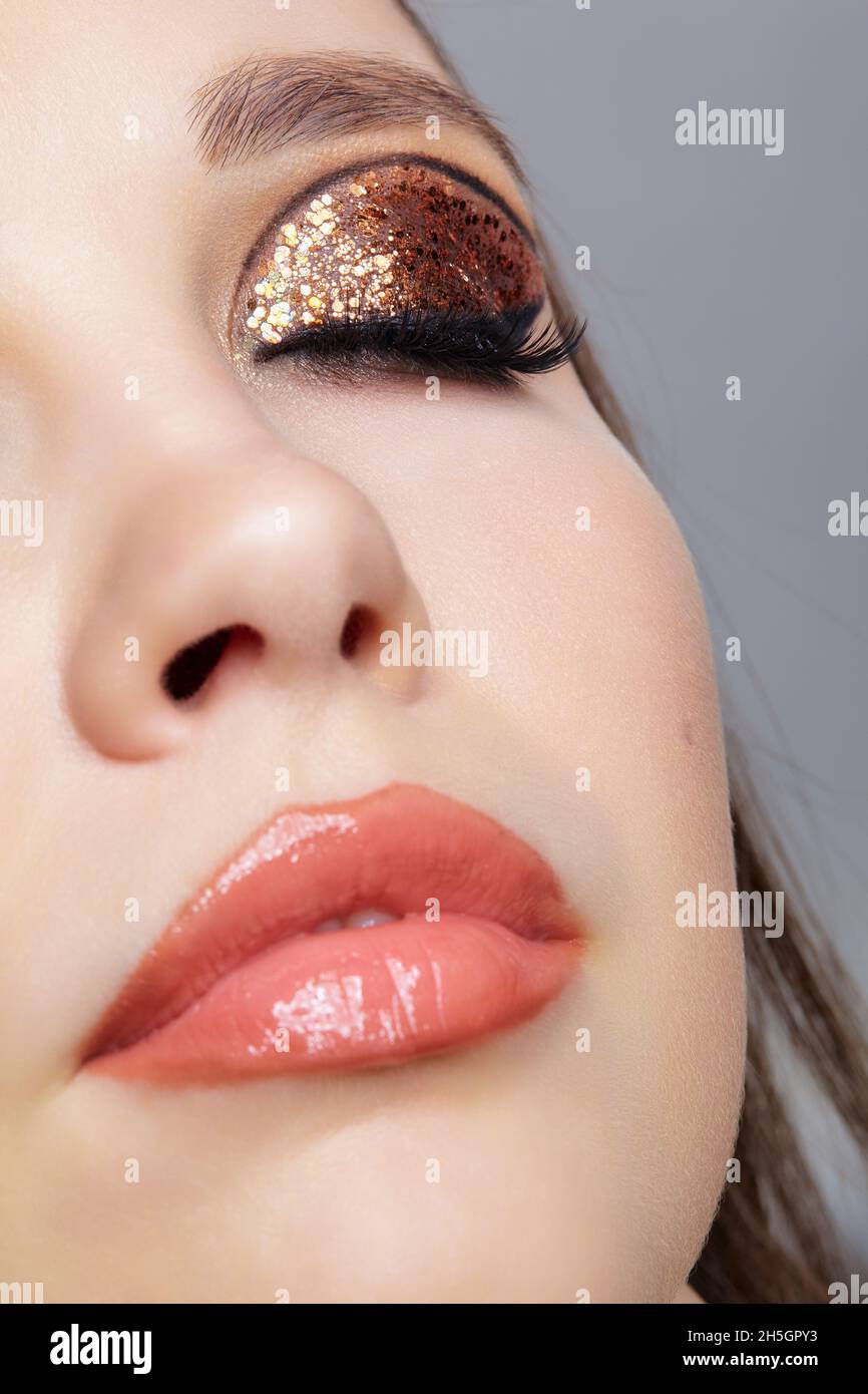 Primo piano di faccia femminile con Vogue dorate lucenti occhi trucco. Occhi chiusi. Foto Stock
