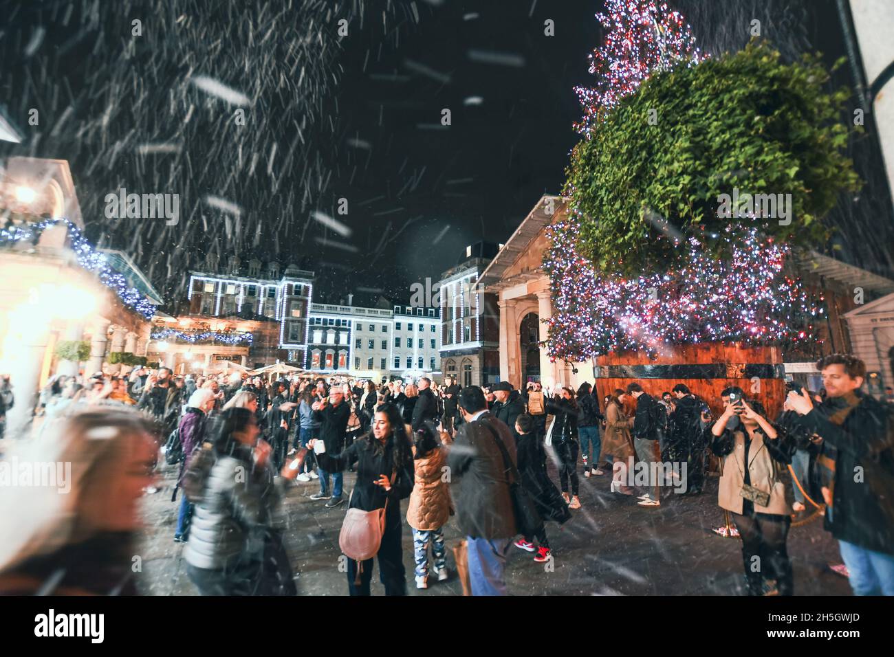 Le luci di Natale di Covent Garden sono state accese il 9 novembre 2021. La neve cadde attraverso gli acquirenti mentre scattavano foto dell'albero. L'albero è dotato di 50,000 luci a LED. Foto Stock