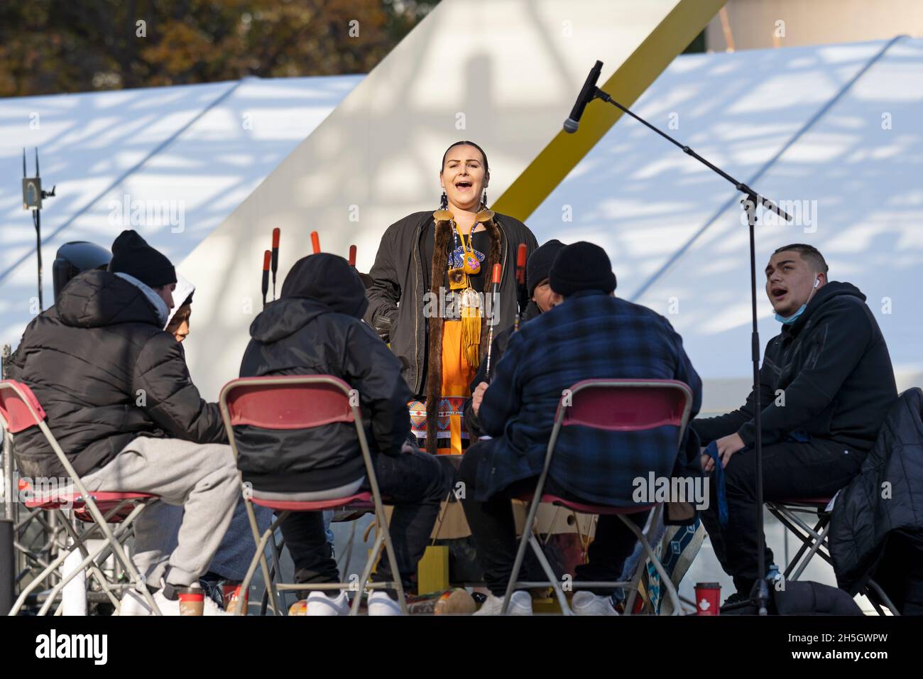 Giovane donna indigena Danielle Migwans con tutti i cantanti a tamburo grande nazione / batteristi al raduno Indigenous Legacy 4 novembre 2021 Toronto, Canada Foto Stock