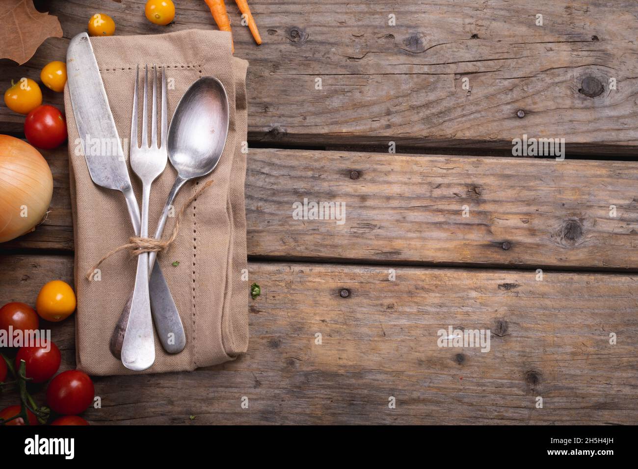 Ingredienti alimentari e molteplici foglie autunnali e posate adagiato su un tovagliolo su una superficie di legno Foto Stock