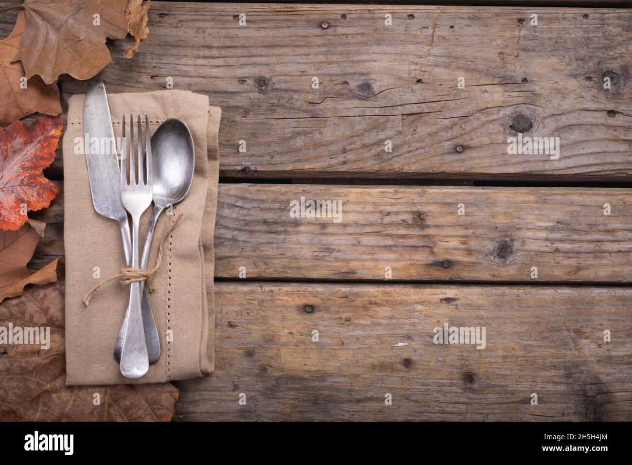 Molteplici foglie autunnali e posate su un tovagliolo su una superficie di legno Foto Stock