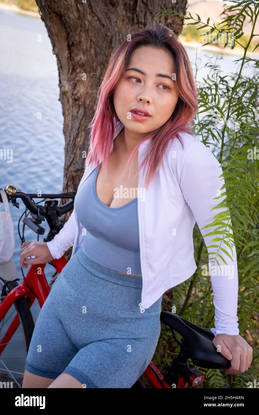 Giovane donna asiatica che si appoggia sul lago della bicicletta Foto Stock