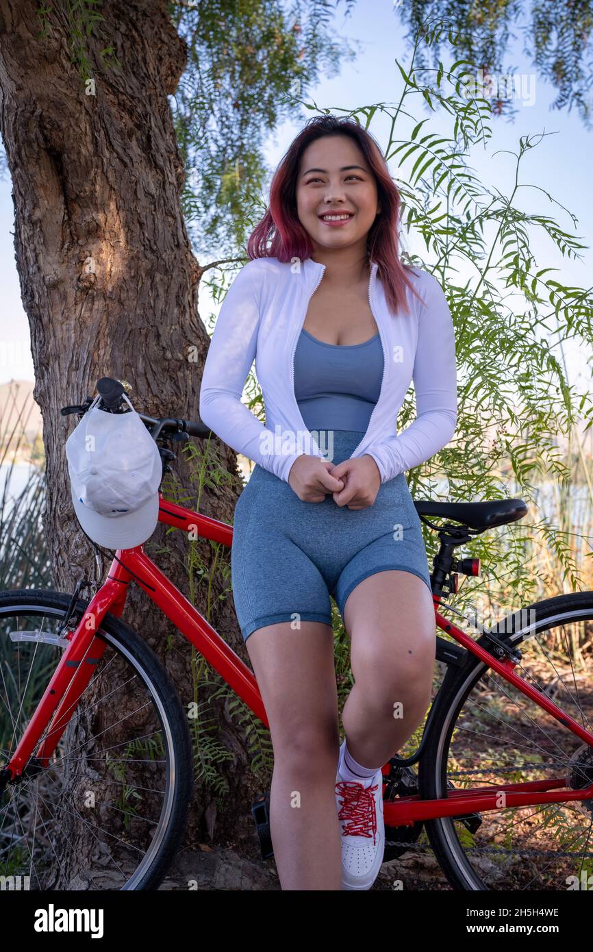 Giovane donna asiatica che si appoggia sul lago della bicicletta Foto Stock