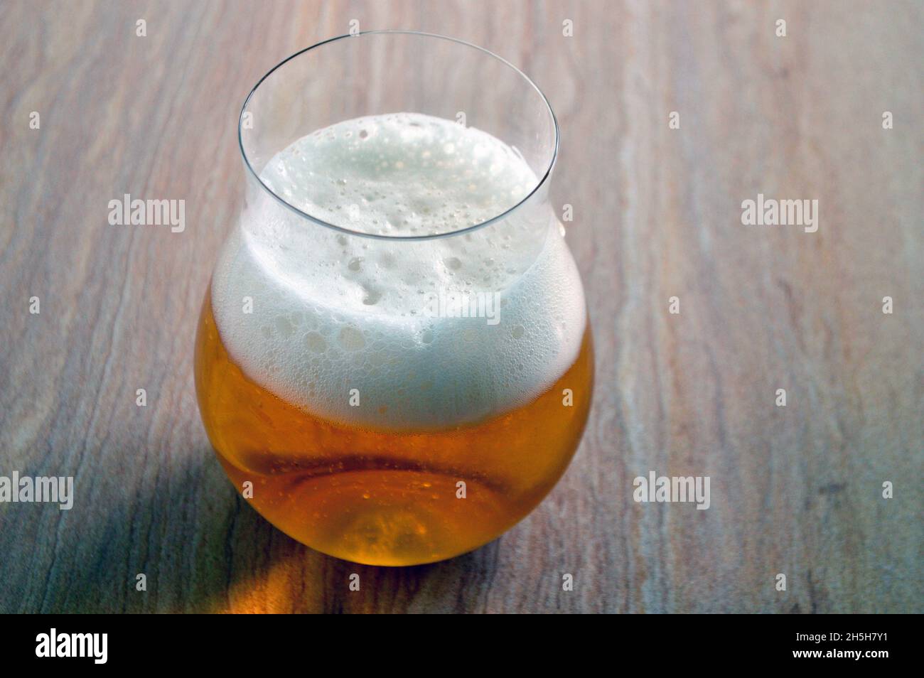Una birra d'oro in un bicchiere sul tavolo Foto Stock