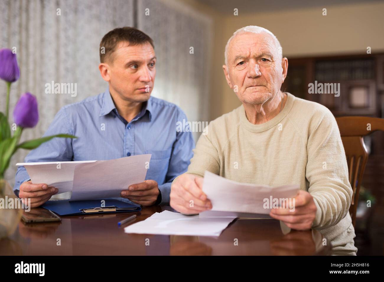 L'uomo maturo e il realtor compila i documenti per l'acquisto di appartamento Foto Stock