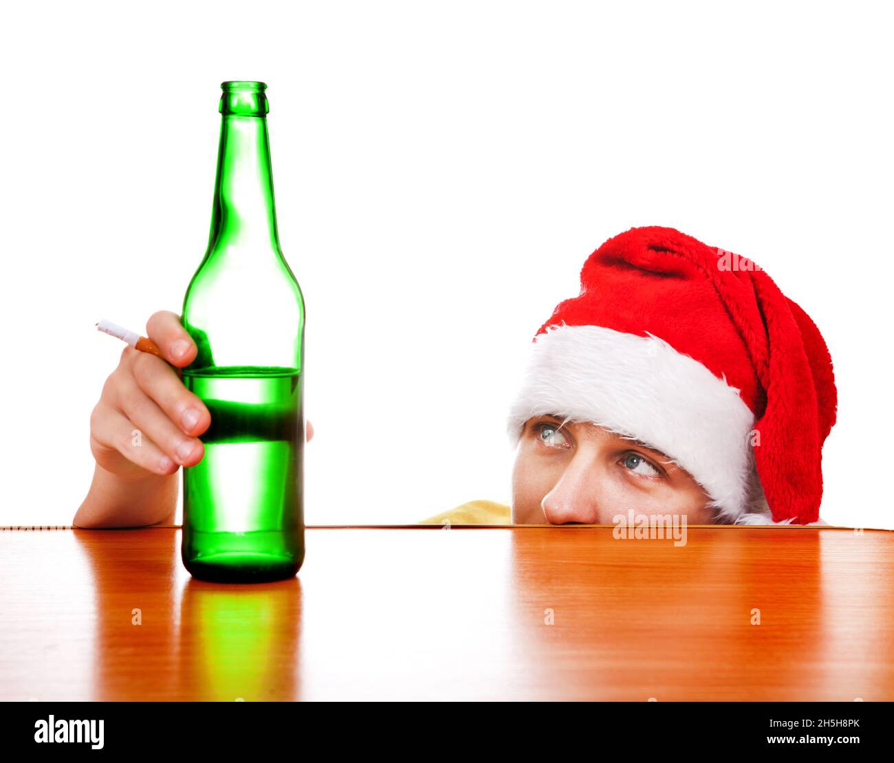 Giovane uomo in cappello di Babbo Natale con la birra al tavolo su sfondo bianco Foto Stock