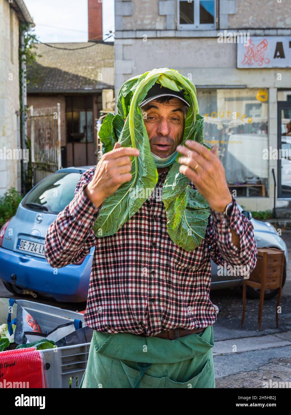 Mercato proprietario stalla scherzando con foglie di cavolo come headdress - Martizay, Indre (36), Francia. Foto Stock