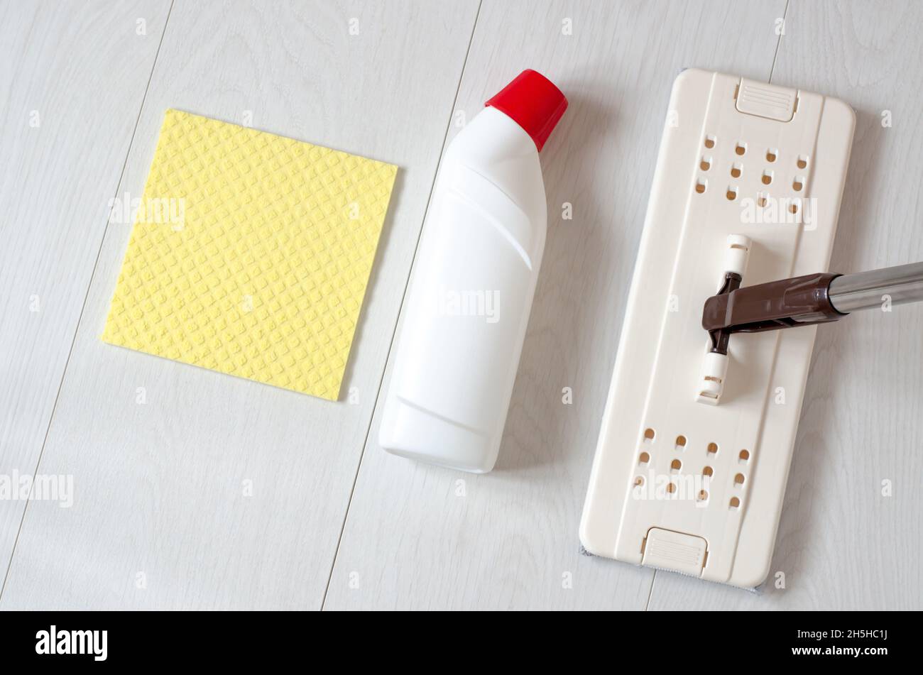 Un mop beige, spugne e una bottiglia di detergente per pavimenti. Prodotti per la pulizia Foto Stock