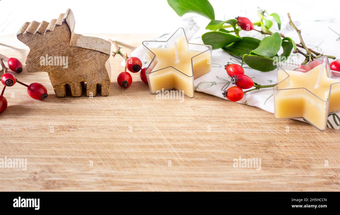 Decorazione per tavolo di Natale alce di legno piccolo, stella forma cera d'ape candele, rosa anca bacche. Primo piano. Foto Stock