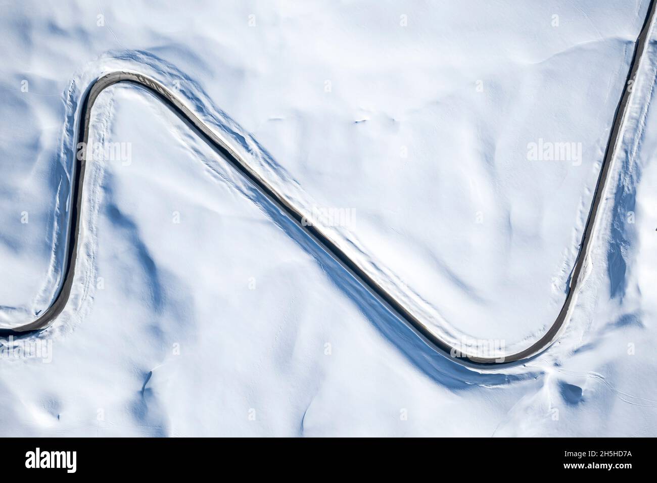 Veduta aerea della tortuosa strada di montagna nel paesaggio innevato invernale, Dolomiti, Italia Foto Stock