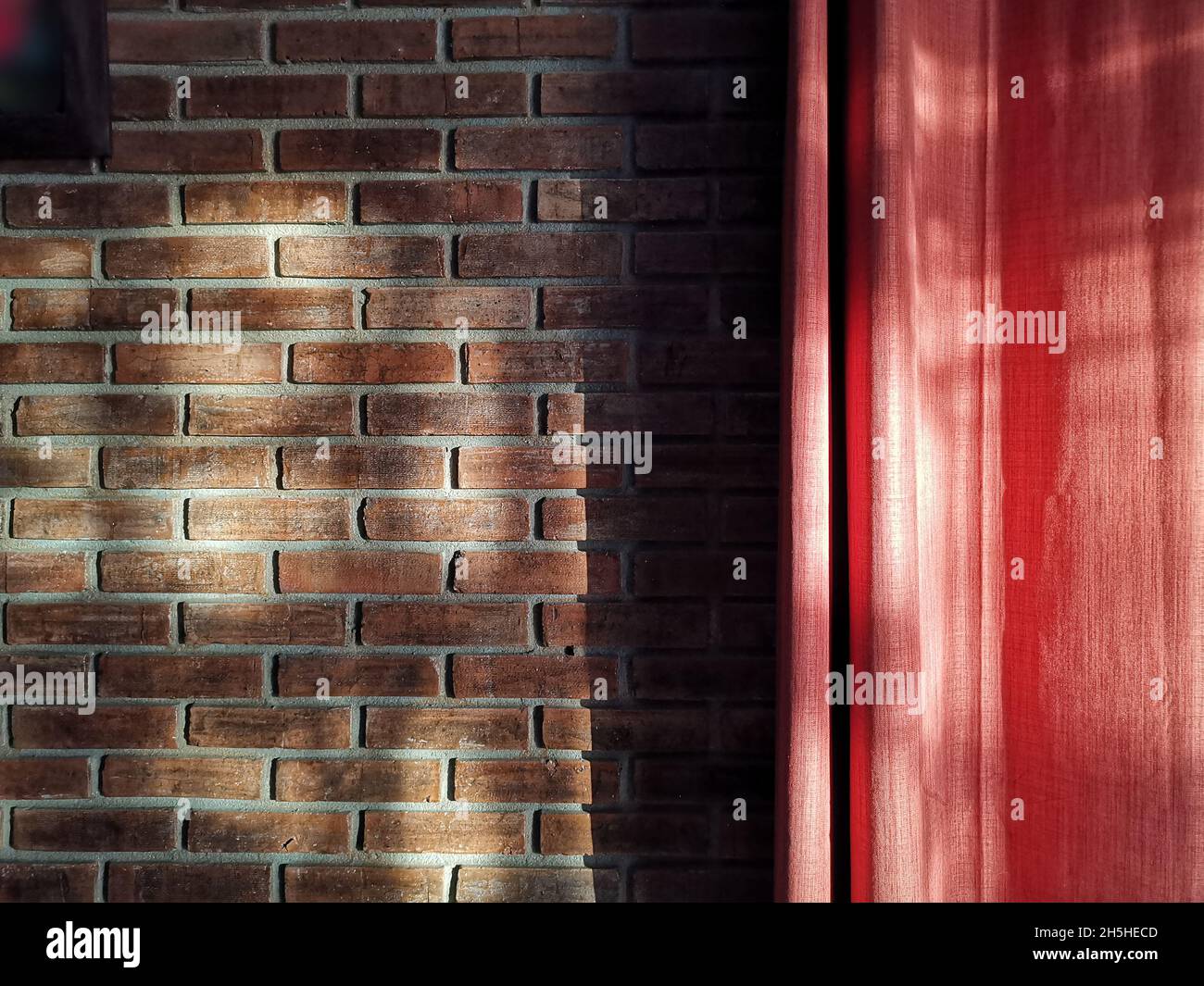 luce del sole su vecchi muri di mattoni e tenda rossa Foto Stock