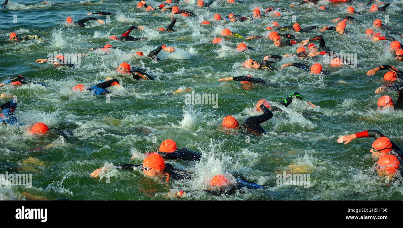 Concorrenti nell'acqua che iniziano la fase di nuoto del triathlon, Foto Stock