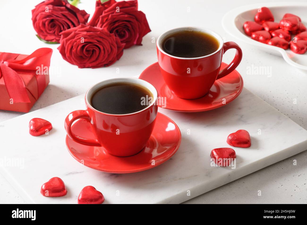 San Valentino datazione con caffè, dolci al cioccolato rosso e rose su bianco. Primo piano. Appuntamento romantico per due. Foto Stock
