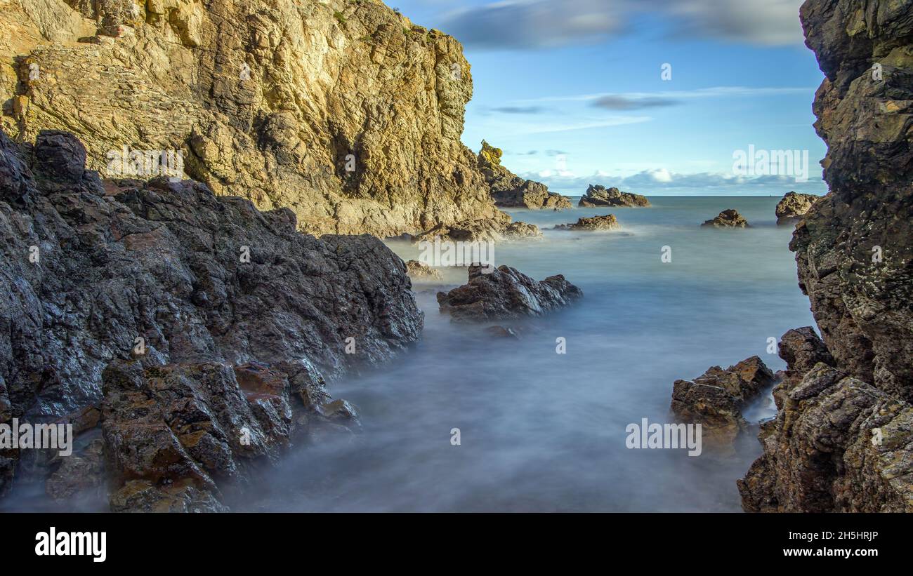 La penisola di Howth Head in giornata soleggiata e nuvolosa, esposizione a lungo, Dublino County, Seashore di scogliere, baie e rocce paesaggio, Irlanda Foto Stock