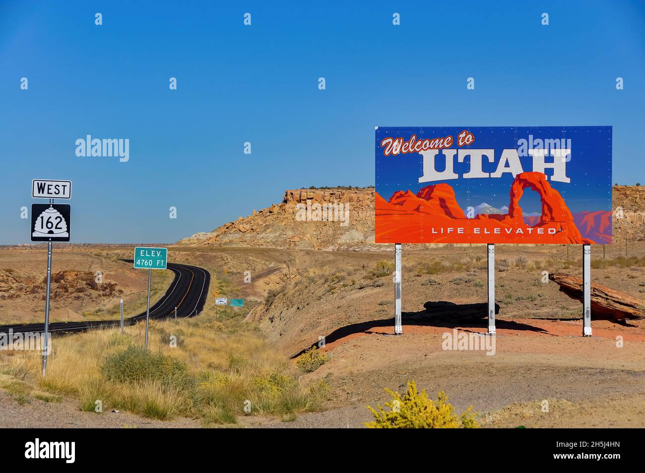 Utah, USA-Luglio 2021; vista del cartello Welcome to Utah sulla linea Colorado-Utah state con sullo sfondo la Route US 162 West che si snoda attraverso il deserto Foto Stock