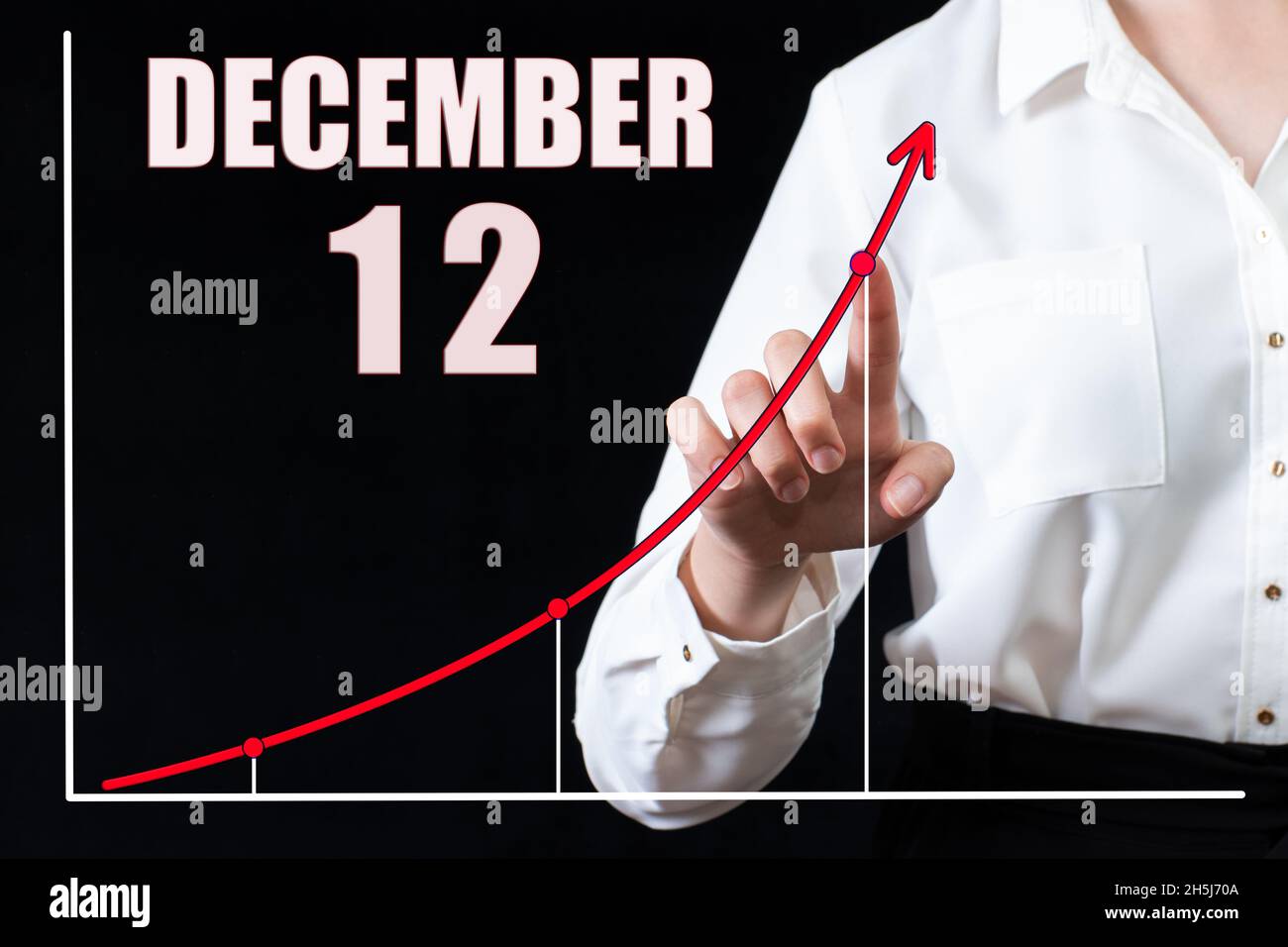 12 dicembre. La mano di una donna d'affari indica il grafico e un calendario con la data del 12 dicembre. Obiettivi aziendali per il giorno. Inverno mont Foto Stock