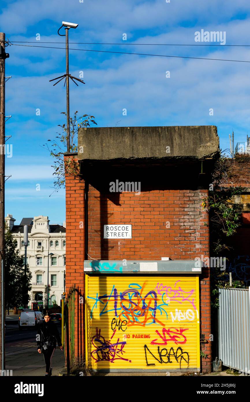 Roscoe Street, nel centro di Liverpool. Donna che cammina e telecamera cctv con grafitti. Foto Stock