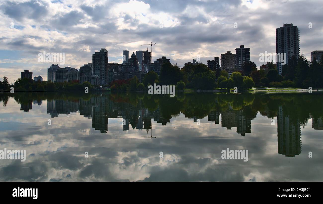 Vista del lago Lost Lagoon in Stanley Park, Vancouver, British Columbia, Canada con lo skyline del distretto Westend riflesso nelle acque lisce. Foto Stock