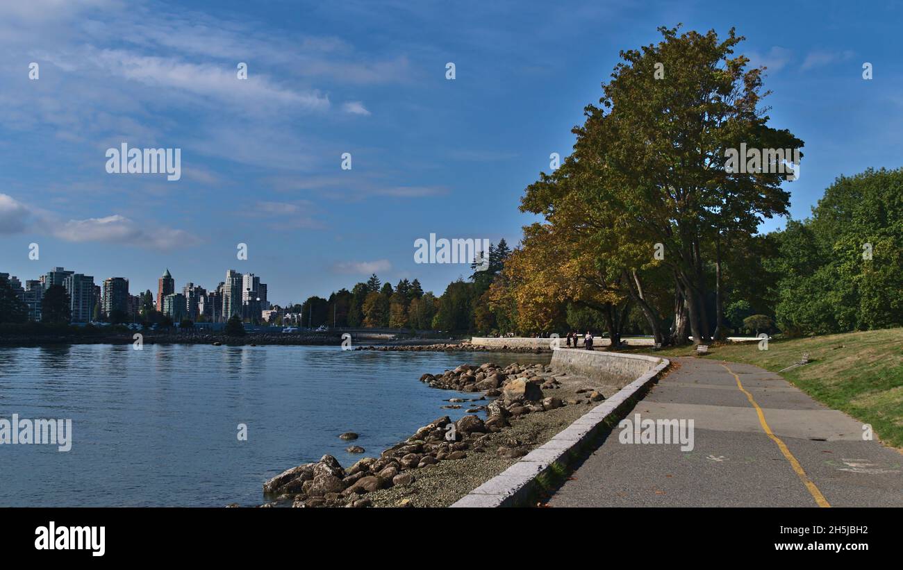 Vista del famoso Seawall, un sentiero a Stanley Park, Vancouver, British Columbia, Canada con alberi colorati in autunno, porticciolo e skyline. Foto Stock