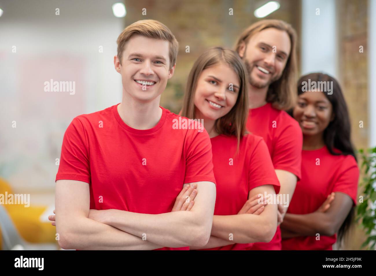 Giovani in magliette rosse che guardano gioiosi e felici Foto Stock