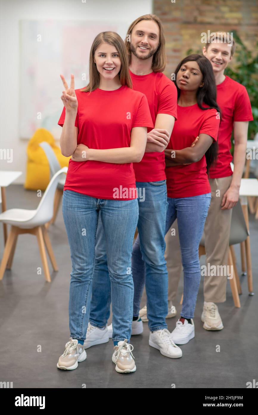 Giovani in magliette rosse che guardano gioiosi e felici Foto Stock