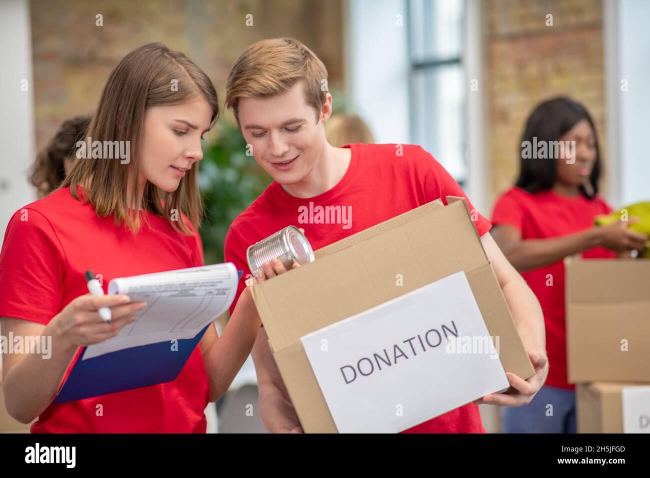 Volontari in rosso thsirts che prendono parte se la distribuzione delle donazioni Foto Stock