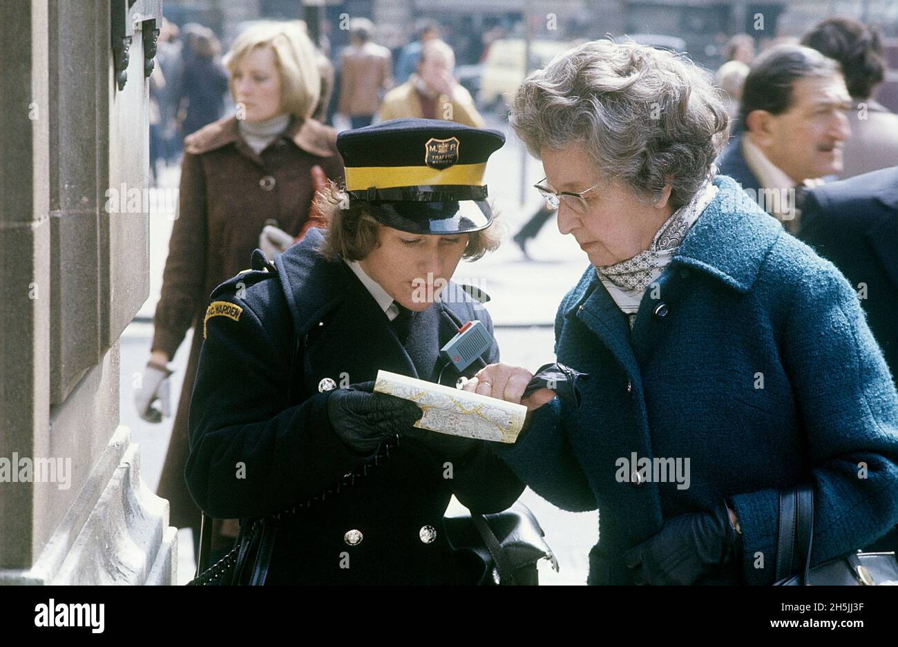 Londra 1982. Una vista sulla strada di Londra e un guardiano del traffico cercando di aiutare una signora anziana a trovare la sua strada. Ha una mappa ed entrambi la stanno guardando. Credit Roland Palm. Foto Stock