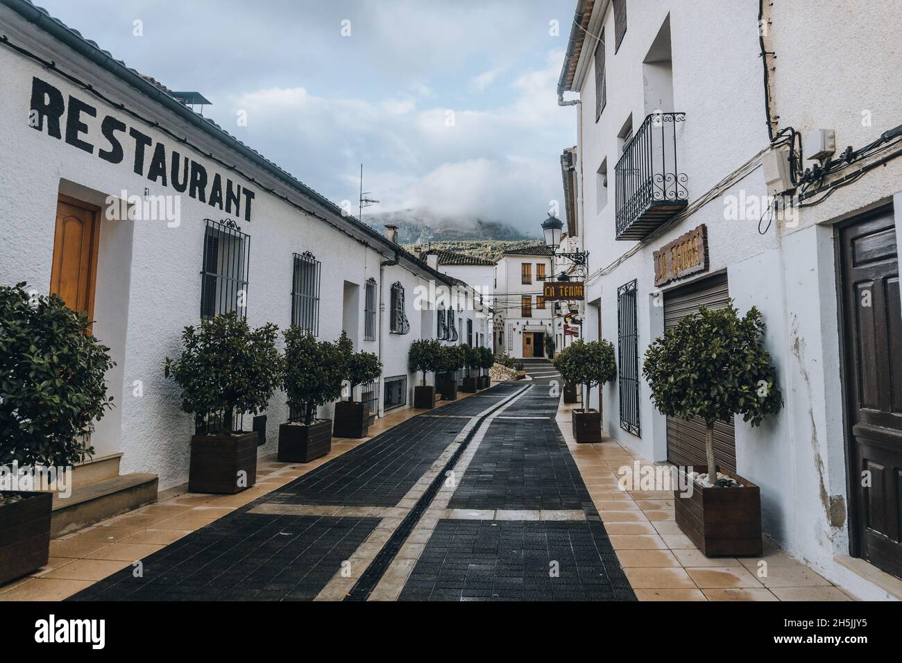 Bella strada bianca antica nella città di Guadalest con molte piante Foto Stock