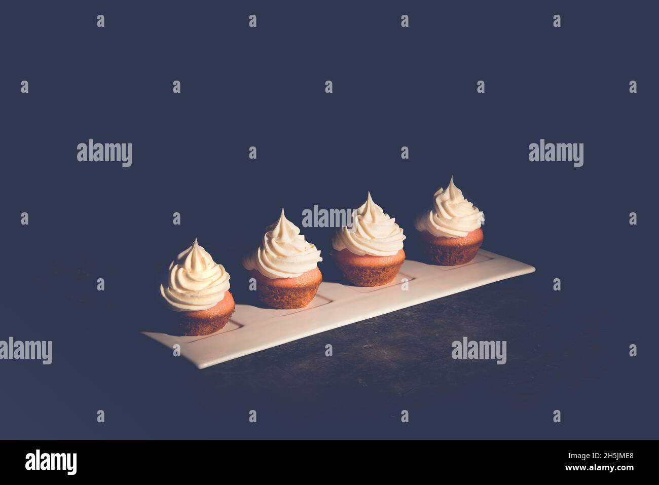 Mini Cupcake con glassa di panna su un piatto bianco Foto Stock