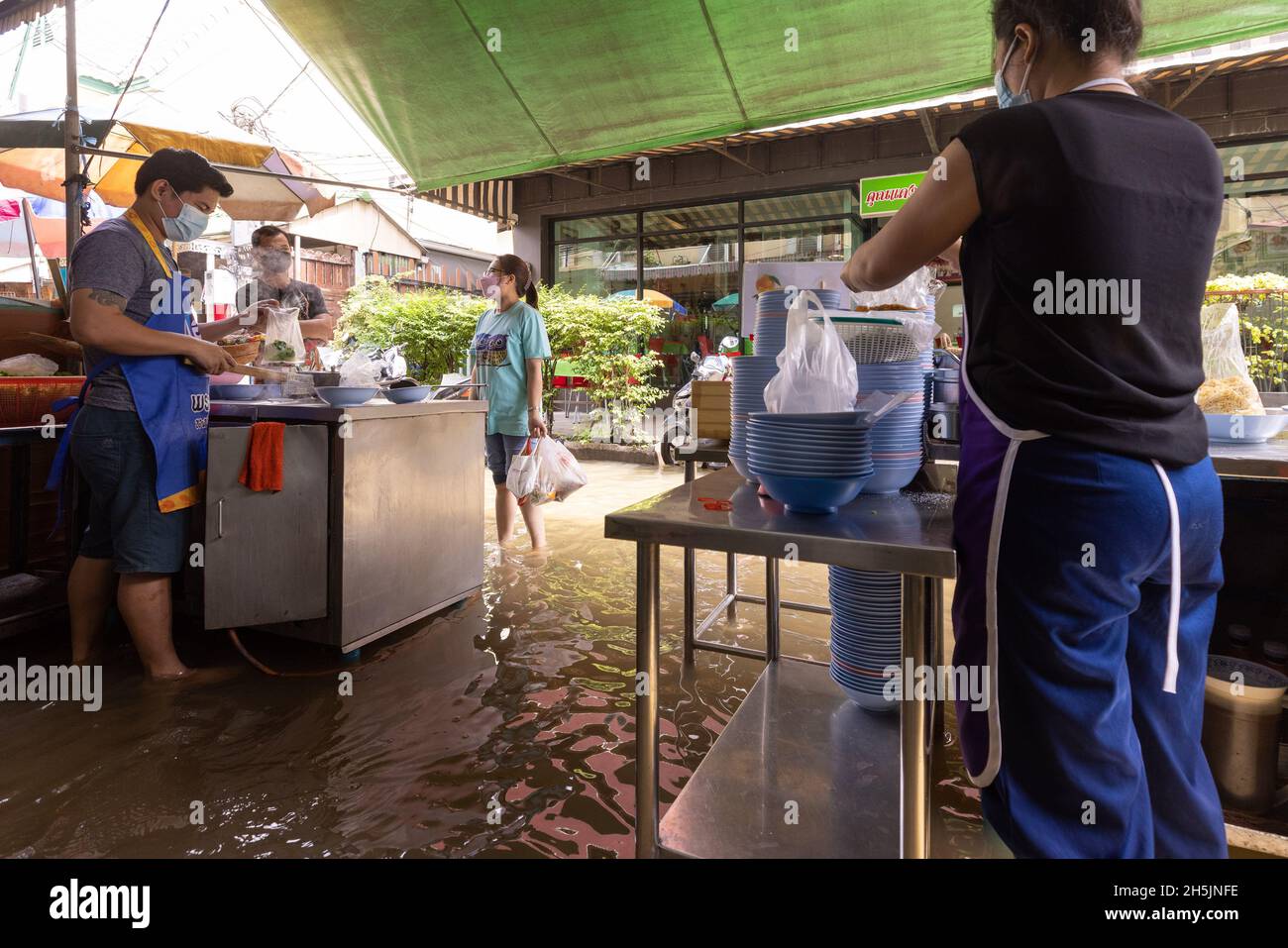 Bangkok, Tailandia. 9 novembre 2021. La gente è veduto ordinare il cibo in un ristorante sommerso.il fiume di Chao Phraya è traboccante influenzato dalle piogge pesanti che causano l'inondazione nel mercato di Wang Lang e molte zone basse giacenti lungo il fiume di Chao Phraya. Credit: SOPA Images Limited/Alamy Live News Foto Stock