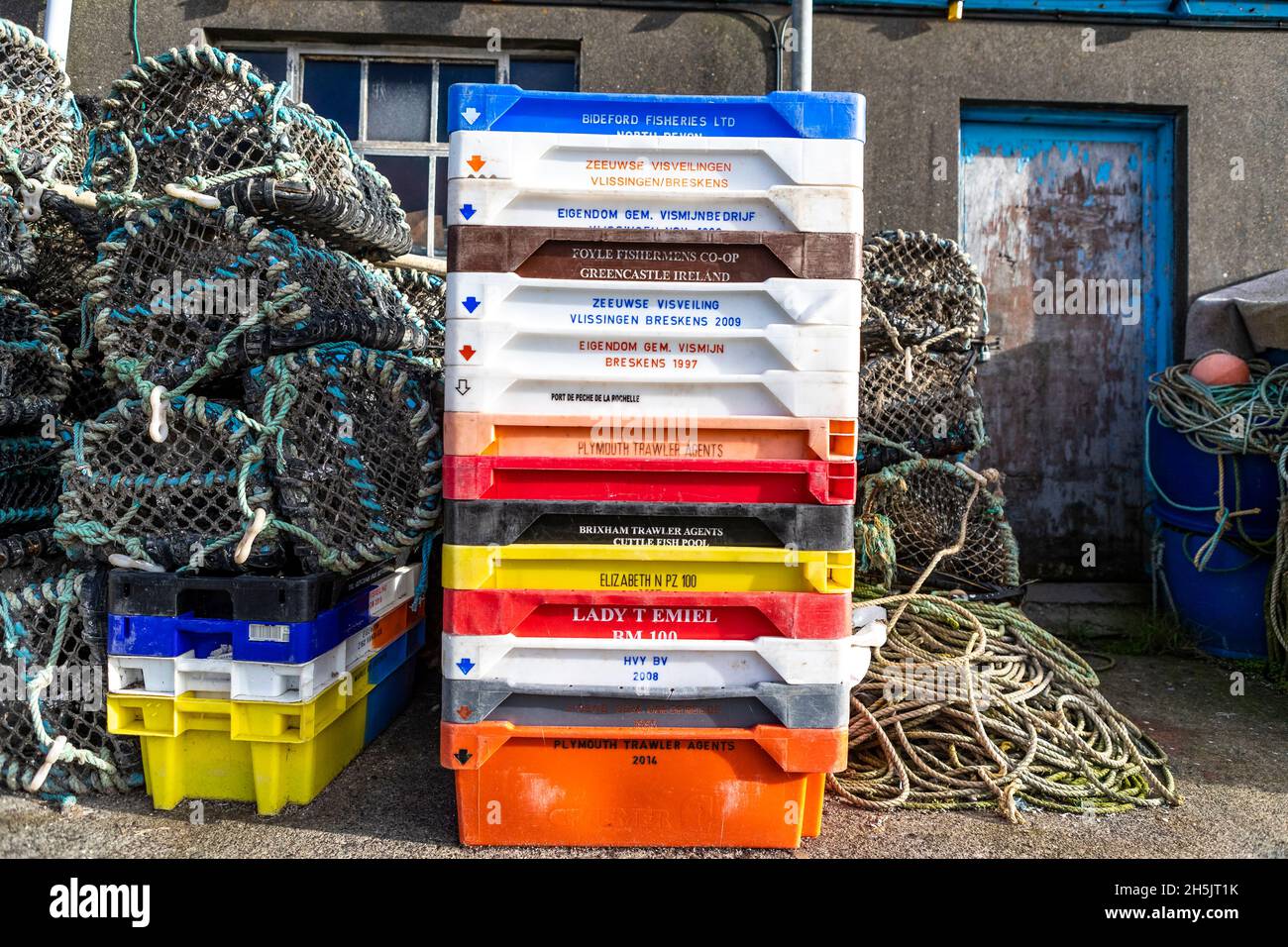 Vasi di aragosta e scatole di pesce accatastati fuori di una casa di pesce. Porto di Newlyn, Cornovaglia. REGNO UNITO Foto Stock