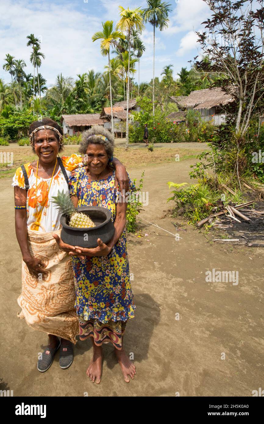 Due donne con ananas a MOU Village, Morobe Bay, Provincia di Morobe, Papua Nuova Guinea; MOU, Provincia di Morobe, Papua Nuova Guinea Foto Stock