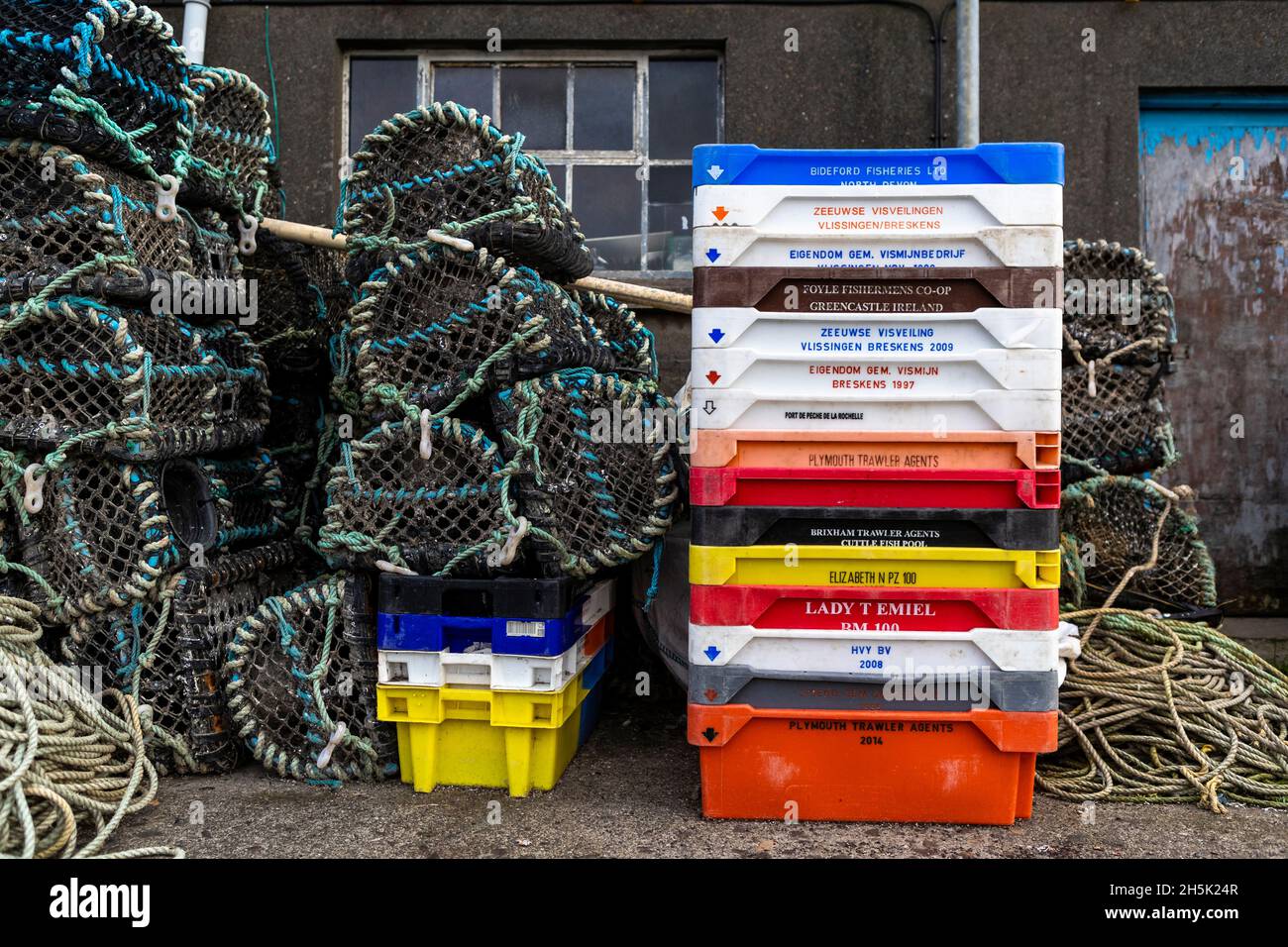 Vasi di aragosta e scatole di pesce accatastati fuori di una casa di pesce. Porto di Newlyn, Cornovaglia. REGNO UNITO Foto Stock